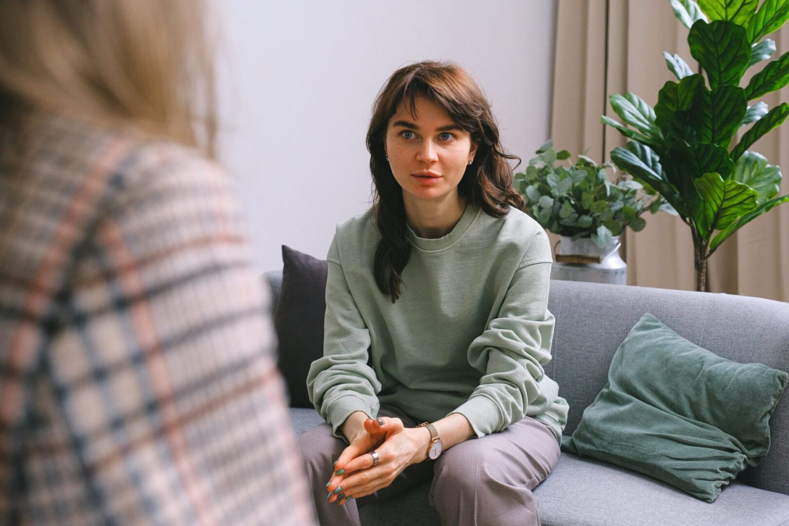 A woman sitting on the couch talking to another person.